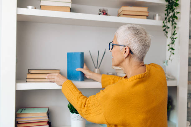 istock Senior woman choosing a book for reading at home 1283079669
