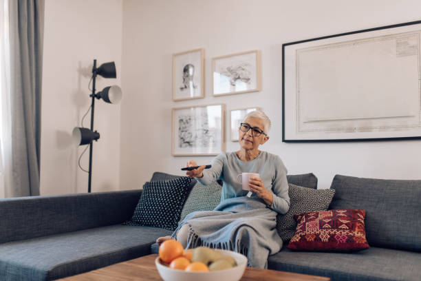 istock Senior woman enjoying coffee and TV program at home 1283080453