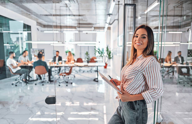 istock Woman standing with laptop in a modern bright office. 1283084422
