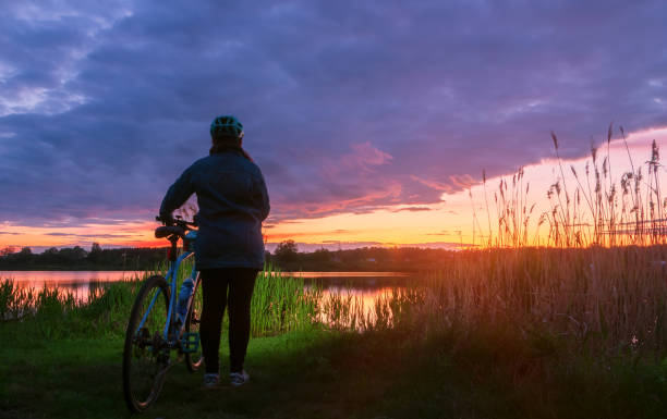 istock Girl with a bicycle on the lake at sunset. 1283086347
