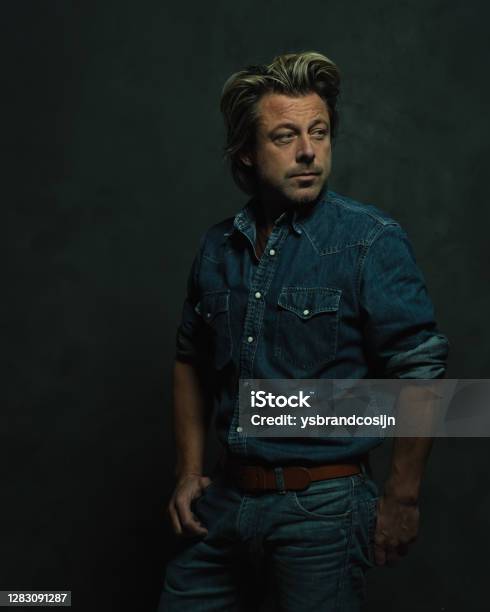 Atmospheric Dark Studio Portrait Of A Tough Middleaged Man With Blonde Hair  In A Jeans Shirt Stock Photo - Download Image Now - iStock