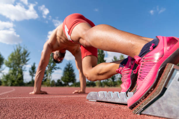 istock Runner using starting block to start his run on race track. Runner using starting block to start his run on running track in a stadium. Athlete starting his sprint on an all-weather running track. 1283091632