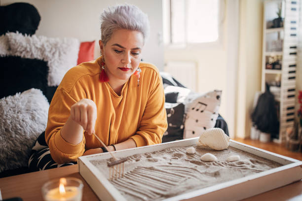 frau spielt mit ihrem zen-garten zu hause - stone zen like buddhism pebble stock-fotos und bilder