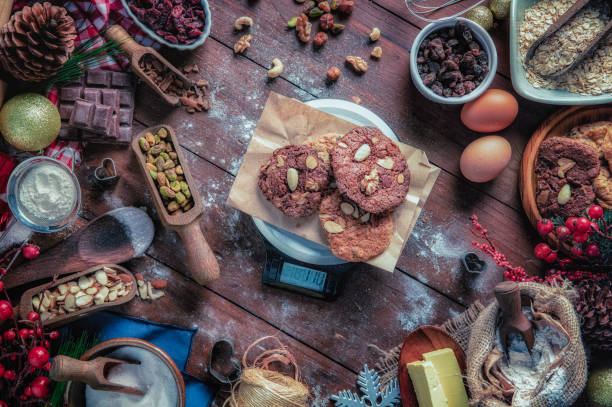 biscotti al cioccolato e noci sulla bilancia digitale del peso alimentare della cucina.  temi natalizi. - biscotti cookie chocolate pistachio foto e immagini stock