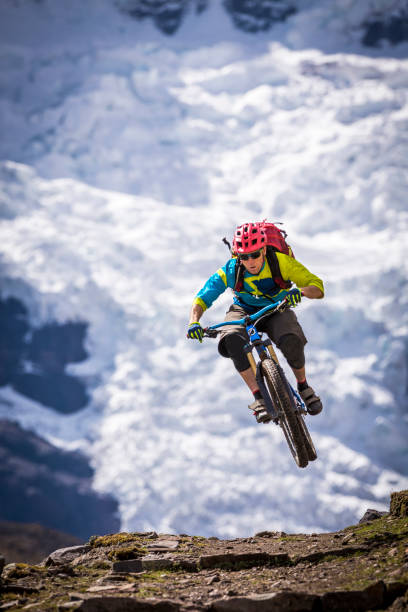 mountain biker com mochila pulando no ar em aventura através de andes. - exploration mountain ice jumping - fotografias e filmes do acervo