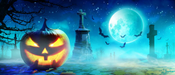 istock Halloween pumpkin face with burning fire inside in the graveyard. 1283095849