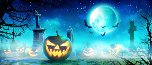istock Halloween pumpkin face with burning fire inside in the graveyard. 1283095889