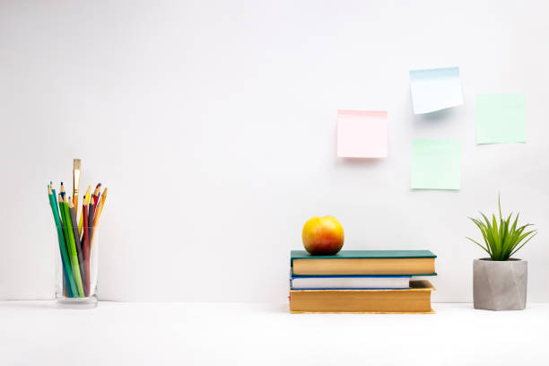 istock white study desk background backdrop. books for learning, stationery on a tabletop. offline home workplace. side view 1283095909