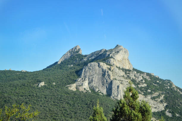 istock Rocky mountain tops covered with green trees against a bright Sunny sky 1283099688