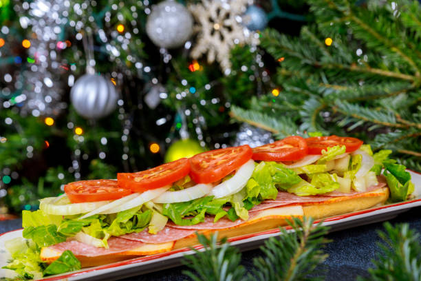 sub largo con queso muenster, salami y verdura sobre fondo de árbol de navidad. - sandwich submarine delicatessen salami fotografías e imágenes de stock