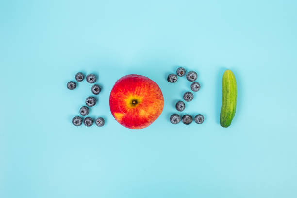 2021 happy new year and new you with fruits and vegetables; blueberries, red apple and cucumber on blue background. goals, healthy, resolution, time to new start and dieting concept - diabetes superfoods imagens e fotografias de stock