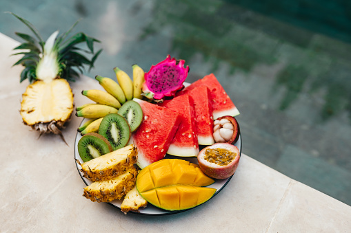 A plate of tropical fruits: watermelon, pineapple, bananas, mangosteen, passion fruit, mango and dragon fruit. Bali Indonesia. Summer time, relaxation travel concept