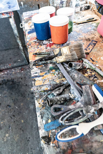 istock Artist's paints in jars and tubes on table with splatter 1283122363