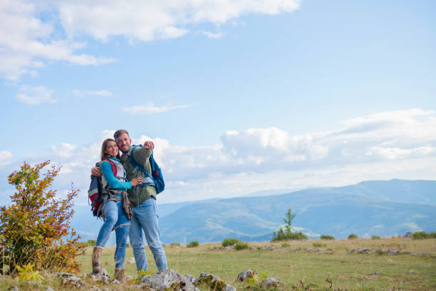 istock Two hikers with backpack standing on top of a mountain and look 1283124003