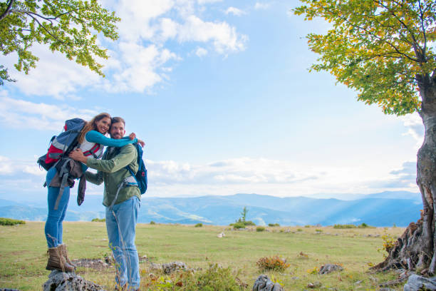 istock Two hikers with backpack standing on top of a mountain and look 1283124730