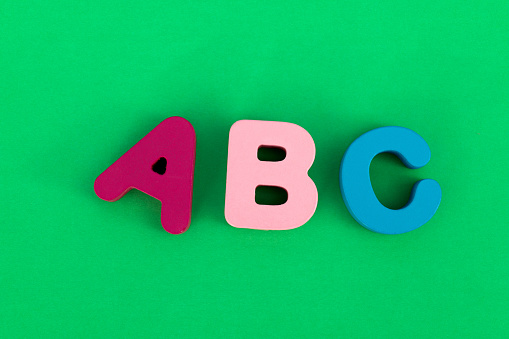 Wooden capital letters A B C on green background.