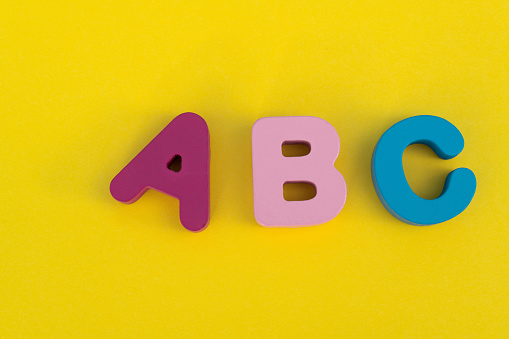 Wooden capital letters A B C on yellow background.