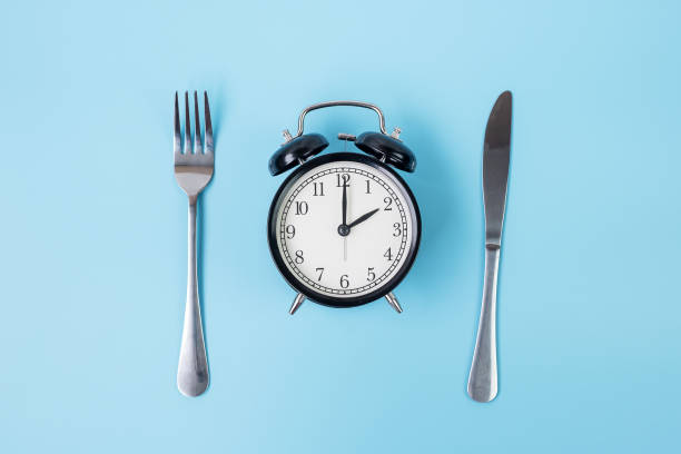 istock Top view alarm clock with knife and fork on blue background. Intermittent fasting, Ketogenic dieting, weight loss, meal plan and healthy food concept 1283128937