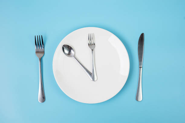 istock Top view white ceramic plate with knife, spoon and fork on blue background. Intermittent fasting, Ketogenic dieting, weight loss, meal plan and healthy food concept 1283129479