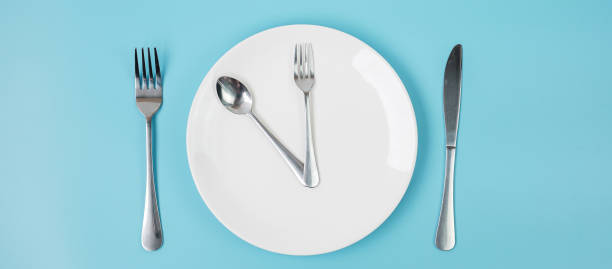 istock Top view white ceramic plate with knife, spoon and fork on blue background. Intermittent fasting, Ketogenic dieting, weight loss, meal plan and healthy food concept 1283129826