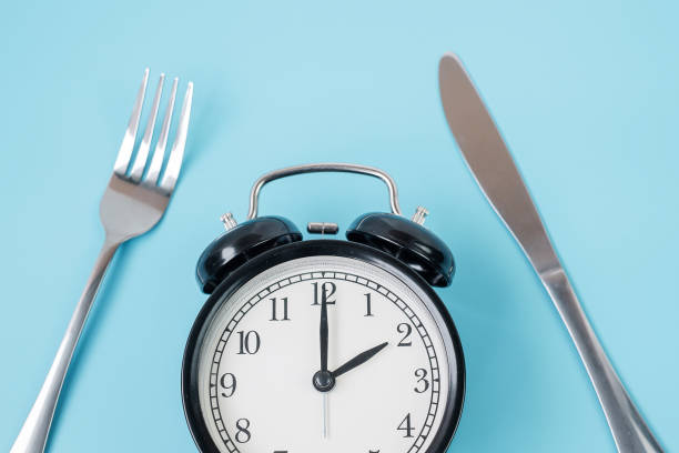 istock Top view alarm clock with knife and fork on blue background. Intermittent fasting, Ketogenic dieting, weight loss, meal plan and healthy food concept 1283129949