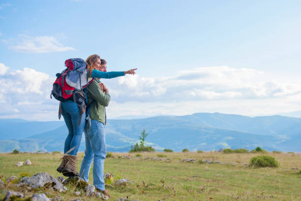 istock Two hikers with backpack standing on top of a mountain and look 1283130772