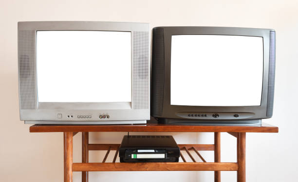 istock Two outdated vintage TVs with VCRs with blank white screens sit on a vintage table in a 1990s tenement building. 1283132579