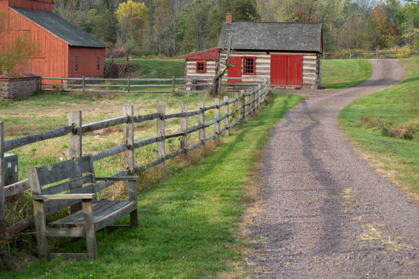 istock idyllic country lane winds past a bench, red barn, and log cabin 1283133029