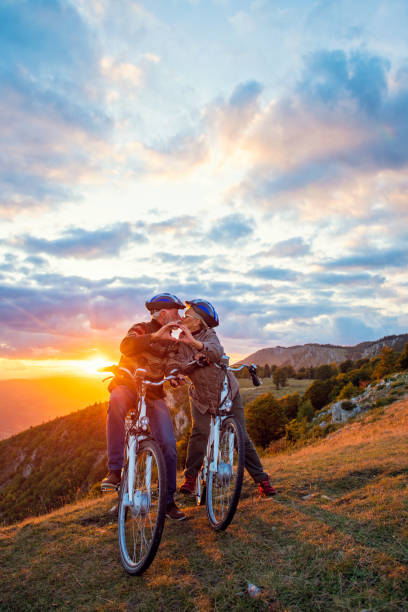 istock Active Senior Couple on bikes making heart shape with hands and kissing. 1283136404