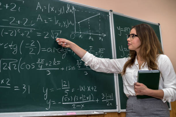 istock Young teacher writing and explain the mathematical formulas on a chalkboard 1283140250