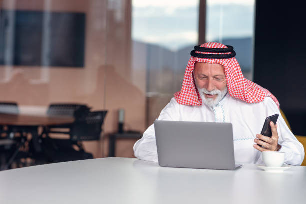 computadora portátil de hombre de negocios árabe en la oficina moderna - headscarf islam senior adult east fotografías e imágenes de stock