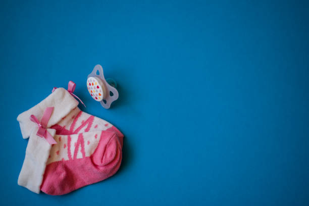 istock Pink baby socks and pacifier on blue background 1283144908