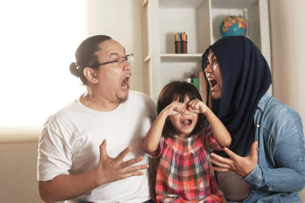 Frustrated little girl daughter scared with mom and dad fighting at home, Asian muslim parents conflict screaming each other makes their baby cries, divorced broken family kid trauma Frustrated little girl daughter scared with mom and dad fighting at home, Asian muslim parents conflict screaming each other makes their baby cries, divorced broken family kid trauma concept divorce children photos stock pictures, royalty-free photos & images