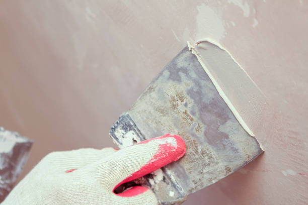 istock Puttying, sealing cracks with gypsum plaster using a spatula. Damaged wall repair. 1283147409