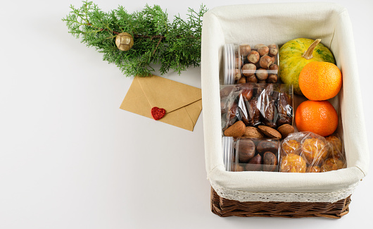 Sweet cookies, assortment of nuts, mandarines and pumpkin packed in craft gift box. Decoration of holiday greeting. Zero waste, eco friendly lifestyle. Diy concept.