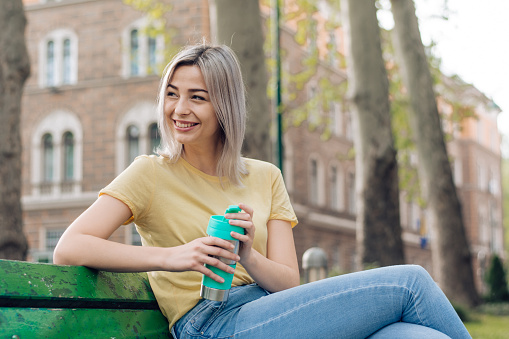 An Asian woman enjoying a simple relaxation with just a cup of coffee and the clean air of a garden in the city.