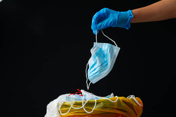 istock Hand putting used dirty surgical mask to  a garbage bin. 1283154291