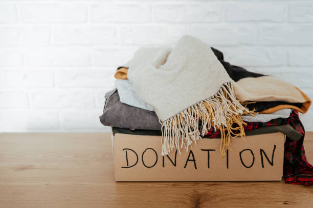 istock Cardboard donation box on the table full with used clothes. 1283154293