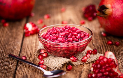 Vintage wooden table with preserved Pomegranate seeds (selective focus; close-up shot)