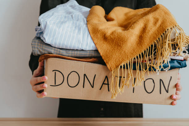 istock Woman holding cardboard donation box full with folded clothes. 1283154301
