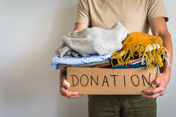 istock Man holding cardboard donation box full with folded clothes. 1283154304