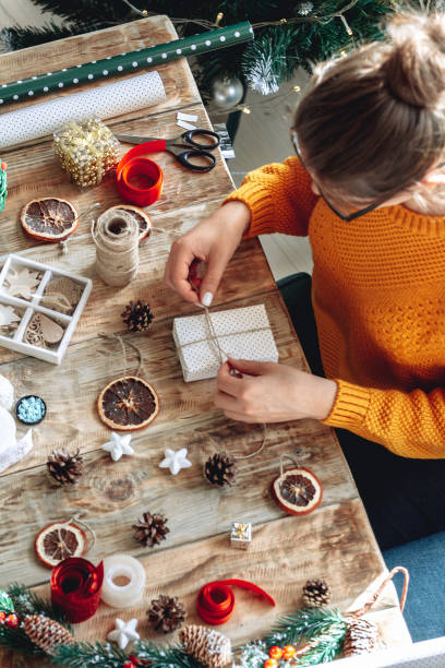 istock Young woman wrapping christmas present on table with new year de 1283154636