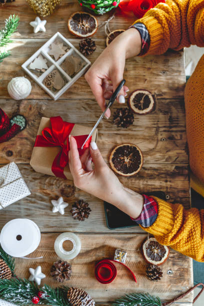 istock Young woman wrapping christmas present on table with new year de 1283155198