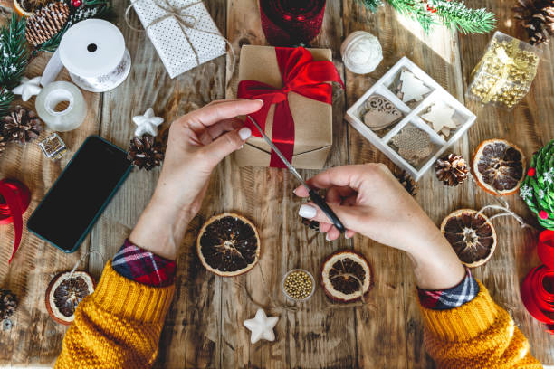 istock Young woman wrapping christmas present on table with new year de 1283155236