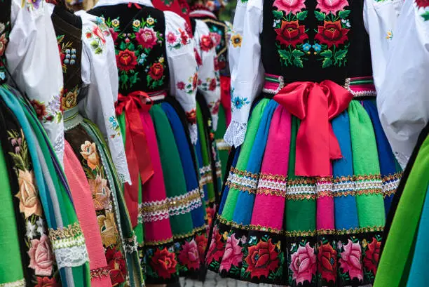 Women dressed in polish national folk costumes from Lowicz region during annual Corpus Christi procession. Close up of traditional colorful striped Lowicz folk skirts and embroidery