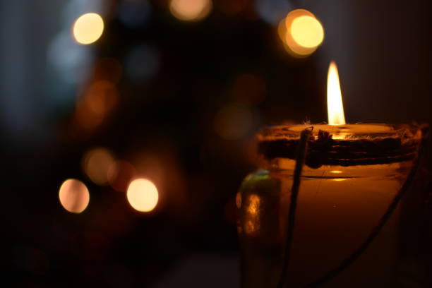 Candle flame in the evening with warm lights in the background stock photo