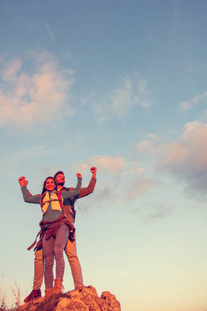 istock Couple on Top of a Mountain Shaking Raised Hands 1283157853