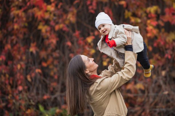 bay with mom in autumn park. mom and daughter in the fall. mom holds the baby in her arms. mother with her little daughter in the autumn park on a walk. - smiling little girls little boys autumn imagens e fotografias de stock