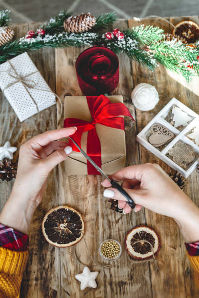 istock Young woman wrapping christmas present on table with new year de 1283158178