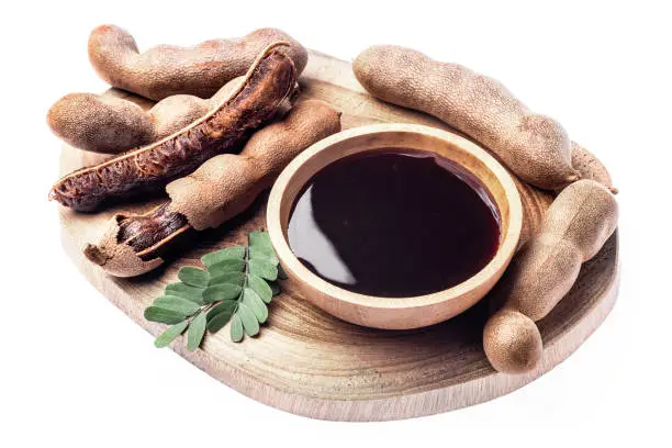 Fresh tamarind sauce with fruits in wooden bowl isolated on white. Healthy food, exotic food.